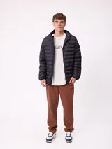 Campera puffer negra con capucha, cierre frontal completo y bolsillos laterales con cierre. Diseño acolchado horizontal con logo de la marca en el pecho.