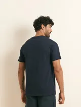 Remera básica de algodón color beige, de manga corta, con cuello redondo y un pequeño detalle bordado en el pecho.