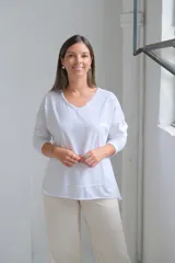 Remera de algodón color blanco, con cuello en V, mangas largas y corte holgado con costuras visibles en el ruedo.