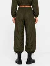 Pantalon estilo parachute verde militar con cintura elastizada ajustable mediante cordón, bolsillos laterales y puños ajustables en los tobillos.