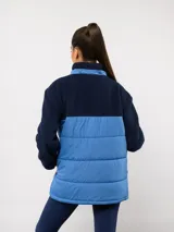 Parka de abrigo Umbro del Club Nacional de Football, con diseño bicolor que combina tejido polar blanco en la parte superior y tejido acolchado azul marino en la parte inferior. Cuenta con cierre frontal completo, cuello alto y bolsillos laterales.