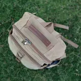 Mochila de tela canvas color beige con detalles en símil cuero marrón. Tiene presillas y broches plásticos para ajustar, bolsillo frontal con cierre, repartición interna para laptop, bolsillos laterales, correas cortas para usar como bolso de mano y correas regulables para la espalda.