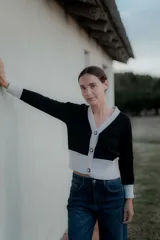 Saco tipo cardigan bicolor con diseño de bloques en blanco y negro, cuello en V, cierre frontal con botones y mangas largas con puños ajustados.