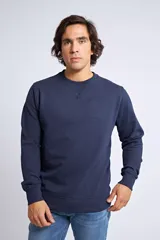 Buzo de cuello redondo en color azul marino, con ajuste regular y mangas largas. Presenta un detalle de costura triangular en el cuello y un logo bordado sutil en el pecho.