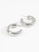 Aros plateados tipo argolla con textura cuadriculada.