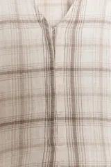 Vestido corto de algodón con estampado de cuadros en tonos beige y marrón. Presenta escote en pico, manga larga con corte evasé y bajo con volantes. Incluye cierre frontal con ganchos metálicos y cremallera lateral oculta.