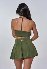 Conjunto deportivo compuesto por un top de escote en V con logo estampado y una pollera tableada de tiro alto, ambos en color verde militar.