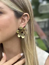 Aros dorados en forma de flor texturizada con doble vuelta de cristales entrelazados.