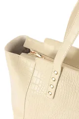 Cartera tipo tote bag de cuero sintético con relieve tipo cocodrilo, color bordó, con doble asa de hombro y detalles de tachas metálicas doradas en la base de las asas.