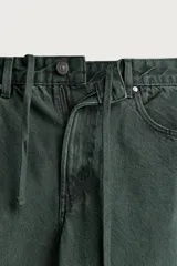 Pantalón barrel fit de mezclilla color verde militar, con efecto lavado, cinco bolsillos, cierre frontal con cremallera y botón, y detalle de pinzas en las rodillas.