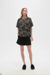 Blusa holgada de viscosa con estampado floral en tonos verde militar y blanco. Presenta cuello a la base, abertura frontal con botones y mangas cortas.