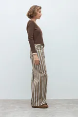 Pantalón de corte recto y tiro medio, con diseño de rayas verticales en tonos marrón, blanco y azul. Cuenta con cierre frontal y bolsillos laterales.