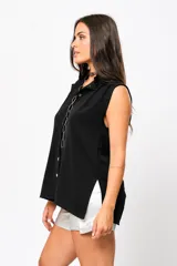 Camisa negra sin mangas con cuello mao adornado con un delicado volado y cierre frontal con botones.