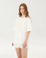 Remera oversize blanca de corte amplio, con cuello redondo y mangas cortas de hombros caídos.