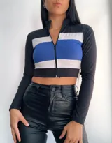 Top manga larga con cierre frontal y diseño tricolor con franjas horizontales en negro, blanco y rojo, fucsia, violeta o azul.