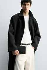 Cartera negra rectangular con diseño trenzado y correa fina para colgar.