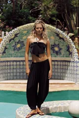 Pantalón bombacho negro confeccionado en tejido satinado, de tiro medio con cintura elástica y diseño con pliegues.
