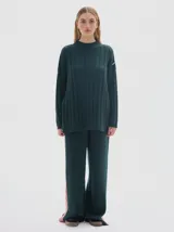 Buzo tejido de punto color beige, con cuello subido, diseño oversized y aberturas laterales en el ruedo.