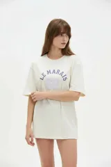 Remera de algodón negra con cuello redondo y mangas cortas, de corte holgado. Presenta estampado frontal en tonos de verde con la inscripción 'New York City Brooklyn' y el logo 'NY' rodeado de laureles.
