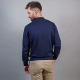 Buzo de punto color beige con cuello alto y medio cierre frontal.