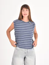 Remera sin mangas de corte holgado, con diseño de rayas horizontales blancas sobre fondo azul. Presenta cuello redondo y hombros ligeramente estructurados.