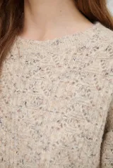 Buzo de punto con cuello redondo, manga larga y textura jaspeada en tonos beige y crema.