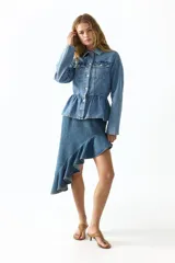 Pollera midi de denim de algodón rígido, con diseño asimétrico, tiro medio, pinzas en la cintura y volado con volumen en el borde inferior.