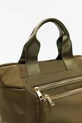 Cartera negra de nylon con diseño compacto y funcional. Cuenta con asas cortas y correa regulable desmontable para llevar al hombro o cruzada, además de múltiples bolsillos con cierre y detalles dorados.