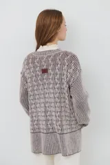 Buzo reversible de tejido de punto con diseño de trenzas, cuello redondo y mangas largas. Presenta una combinación de colores en contraste, con un lado en violeta y el otro en marrón oscuro.