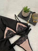 Conjunto de lencería compuesto por un corpiño triangular y una tanga, ambos confeccionados en lycra color beige con detalles de encaje negro y elásticos a tono.
