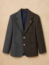 Blazer oversize de diseño bicolor con estructura asimétrica, combinando un lado en color negro y otro en color marrón, ambos con estampado de rayas diplomáticas. Presenta solapas clásicas, cierre frontal con botones de strass y un pin decorativo en forma de perro salchicha.
