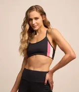 Top deportivo negro con recortes laterales en rosa y blanco, breteles finos y sin copa.