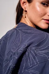 Campera bomber de algodón color azul, con diseño de bordado floral en tono sobre tono, cierre frontal y mangas largas con puños elásticos.