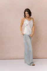 Jean wide leg tiro alto de lavado claro, con diseño de cinco bolsillos, cierre frontal con botón y aplicación de strass en degradé a lo largo de los laterales.