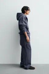 Pantalón jogger de corte wide fit confeccionado en algodón con interior de rizo. Presenta cintura elástica ajustable con cordón, bolsillos laterales y un bolsillo trasero de plastrón. Cuenta con un efecto lavado y acabados irregulares en el ruedo.