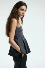 Top strapless de punto con escote recto y diseño ajustado en el torso que se abre en un peplum acampanado en la cintura.