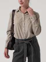 Blusa de manga larga confeccionada en cotelé estampado con patrón geométrico. Presenta cuello camisero, cierre frontal con botones y puños abotonados.