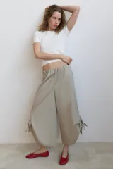 Pantalón tipo culotte de tiro medio con cintura elástica y bolsillos laterales ocultos. Presenta un diseño de pernera ancha con aberturas laterales en el bajo, ajustables mediante cordones con frunces.