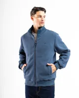 Campera de polar azul con cierre frontal completo y cuello alto. Presenta puños y cintura con elástico acanalado. Tiene un pequeño logo bordado en el pecho.