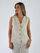 Chaleco sastrero sin mangas, de color beige con diseño de rayas verticales, cuello en V y cierre frontal con botones.