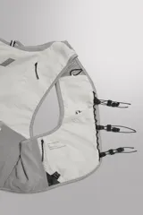 Chaleco deportivo técnico y ligero de color gris, diseñado con tejido de malla transpirable, múltiples bolsillos frontales elásticos, cierres de cordón ajustable y detalles reflectantes, ideal para running y actividades al aire libre.