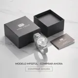 Reloj analógico Mini Focus con caja redonda de metal plateado y malla de acero tipo milanesa. Presenta una esfera minimalista con índices de bastón y números romanos en las posiciones 3, 6, 9 y 12.