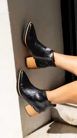 Botinetas de cuero negro con diseño combinado en textura reptil, taco cuadrado de madera y cierre lateral.