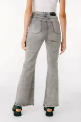 Jean azul claro de corte flare con aberturas en los tobillos y detalles rotos en las rodillas y muslos.