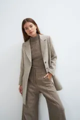 Saco corto entallado de lana fina, con cuello solapa, manga larga y cierre frontal con botones. Presenta un diseño clásico con textura de espiga en tonos tierra.