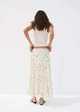 Falda midi evasé de color blanco con estampado floreado en tonos azules y verdes. Cuenta con cierre lateral y forro interior.