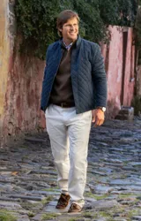 Pantalón de vestir color beige, de corte recto, con bolsillos laterales y traseros. Se ajusta a la cintura con cinturón de cuero marrón.