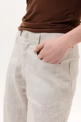 Pantalón color beige de corte wide leg, con bolsillos delanteros y cierre frontal de botón y cremallera.