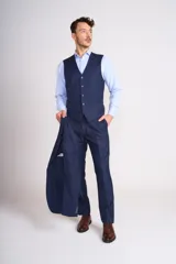 Traje de tres piezas color azul marino con textura sutil. Incluye saco entallado con solapas clásicas, chaleco abotonado y pantalón de corte recto. Se complementa con una camisa celeste de cuello italiano y pañuelo de bolsillo blanco.