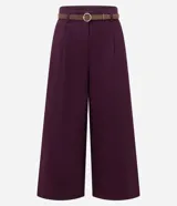 Pantalón pantacourt de sastrería color bordó, con pliegues delanteros, cintura con trabillas y cierre frontal. Incluye un cinturón fino desmontable con hebilla metálica y presenta un corte amplio y sofisticado.
